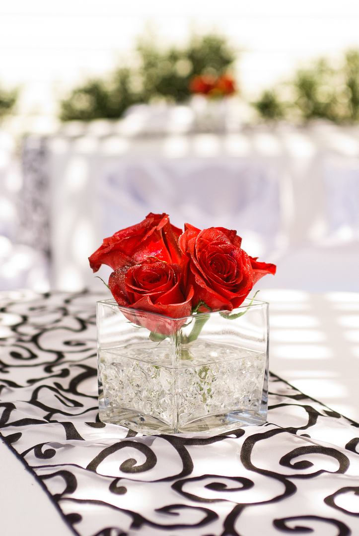 A vase with red roses on top of it.